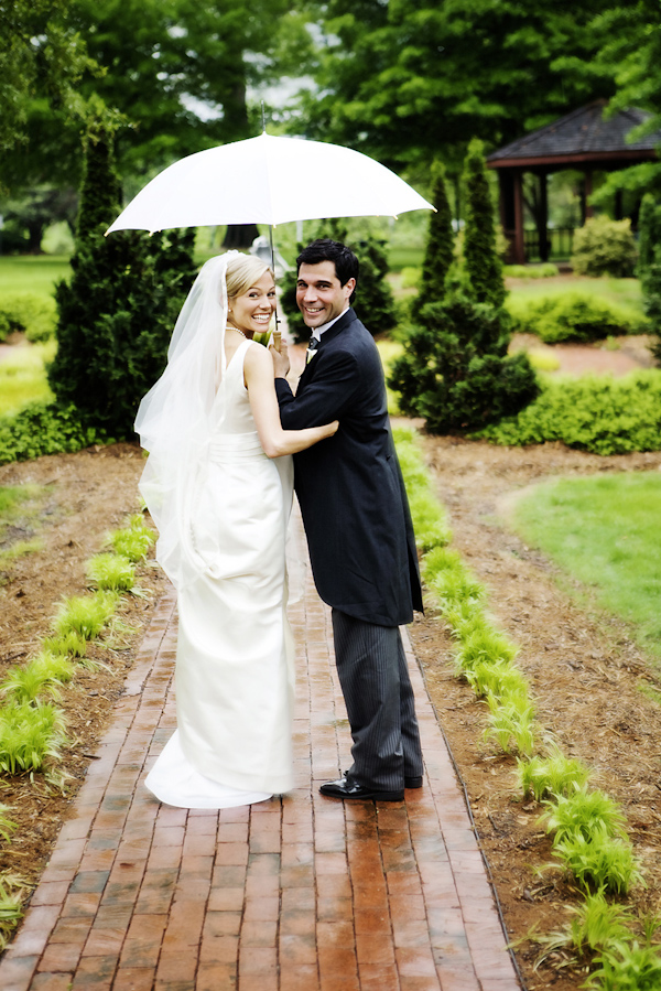 the happy couple standing in the rain under umbrella - photo by North Carolina based wedding photographers Cunningham Photo Artists